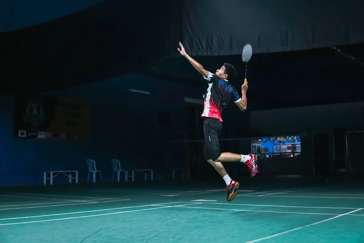 Badminton player hitting a jump smash under lights