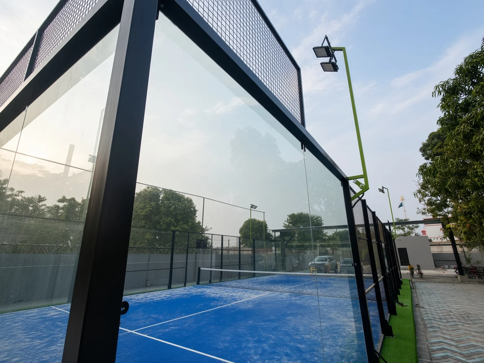 Glass-walled blue padel court at Vybe Sports Arena