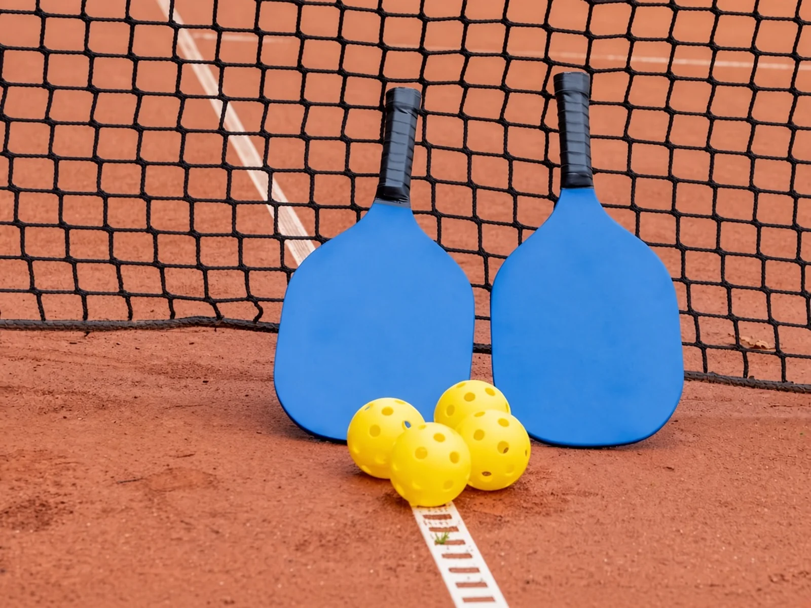 Pickleball paddles and balls by the net